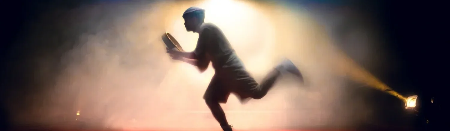 En person i mörka kläder med hjälm springer på scenen under en ljussättning