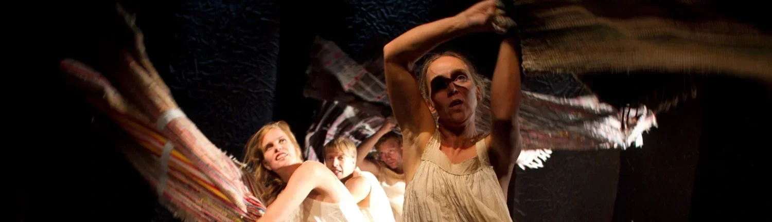 Flera personer vevar i tygstycken över sina huvuden i en teaterföreställning.