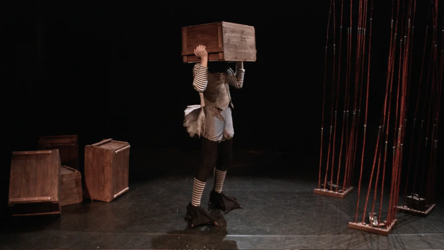 Person på scen omgiven av trälådor och metallstavar.