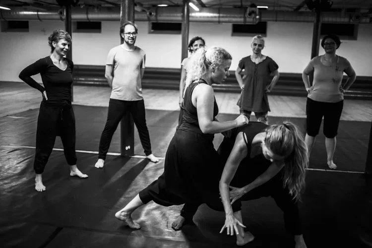 Grupp människor som tränar eller gör en övning i en gymnastiksal.