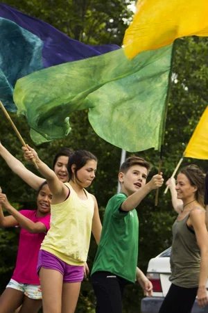 Barn som håller i färgglada fanor utomhus.