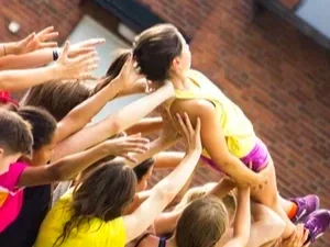 Flera barn som lyfter ett annat barn i utomhusmiljö.