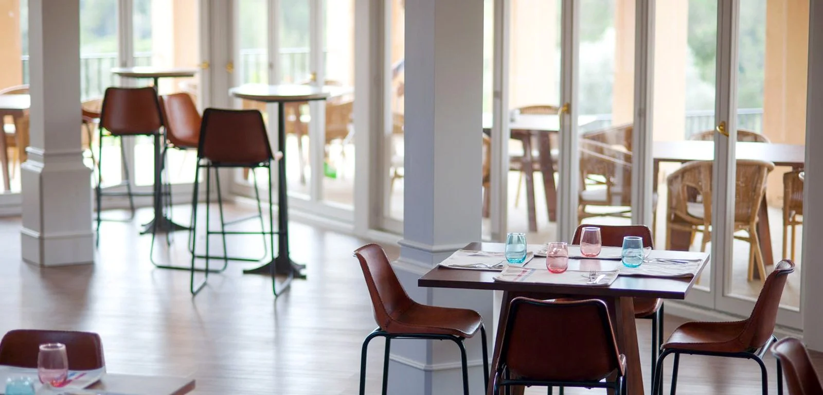 Sala de restaurante vacía con mesas, sillas y vasos de colores