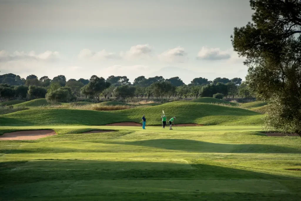 Torneo de golf en un campo amplio con árboles y colinas, con tres jugadores participando en el juego.