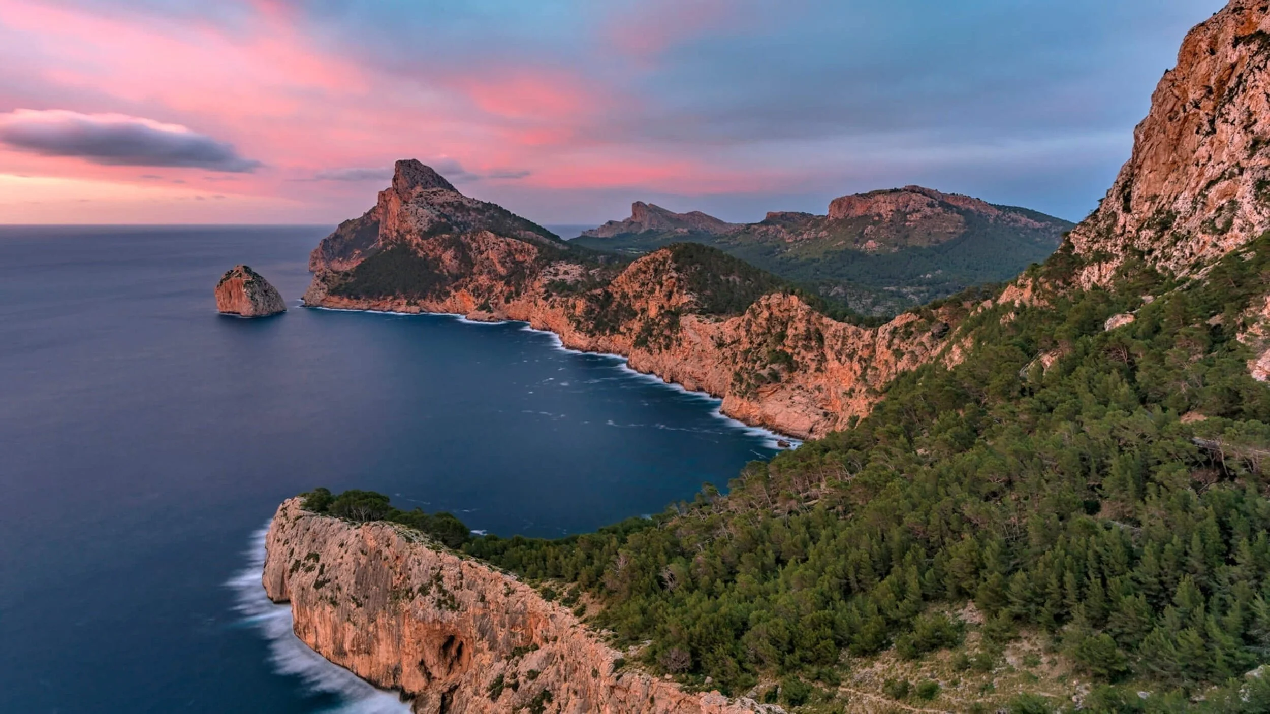 Paisaje costero con montañas y vegetación durante el atardecer