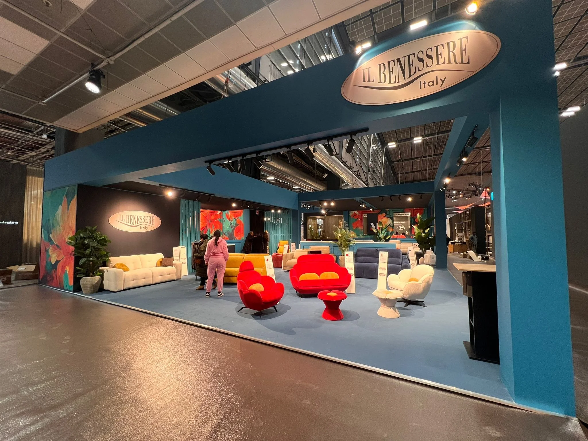 Stand espositivo con mobili in stile moderno e colorato, piante verdi decorative, e un logo che recita 'Il Benessere Italy'.