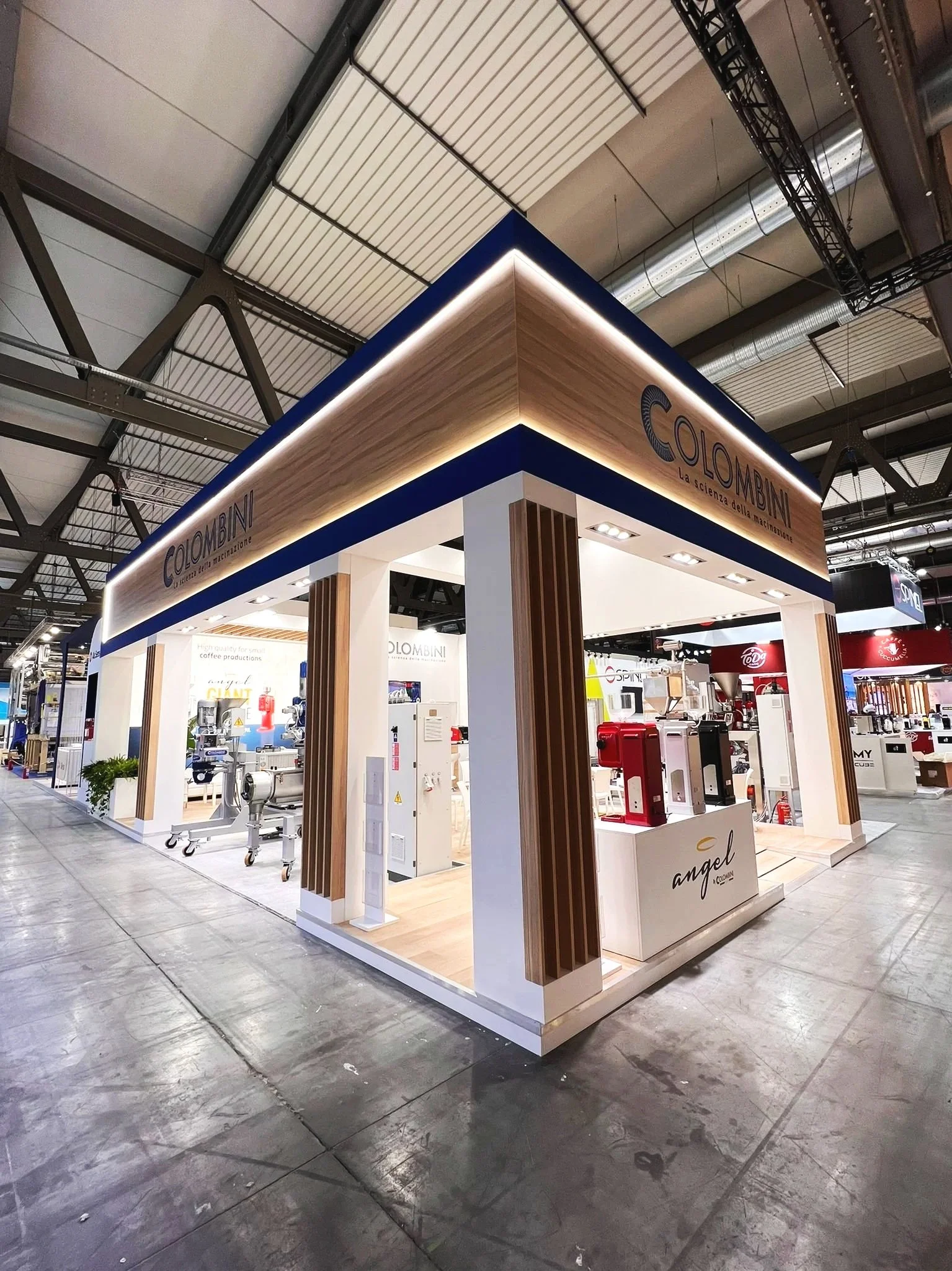 Stand espositivo di un'azienda chiamata Colombini, specializzata in macchine per il caffè, con un design moderno e elegante, situato in una fiera o evento.