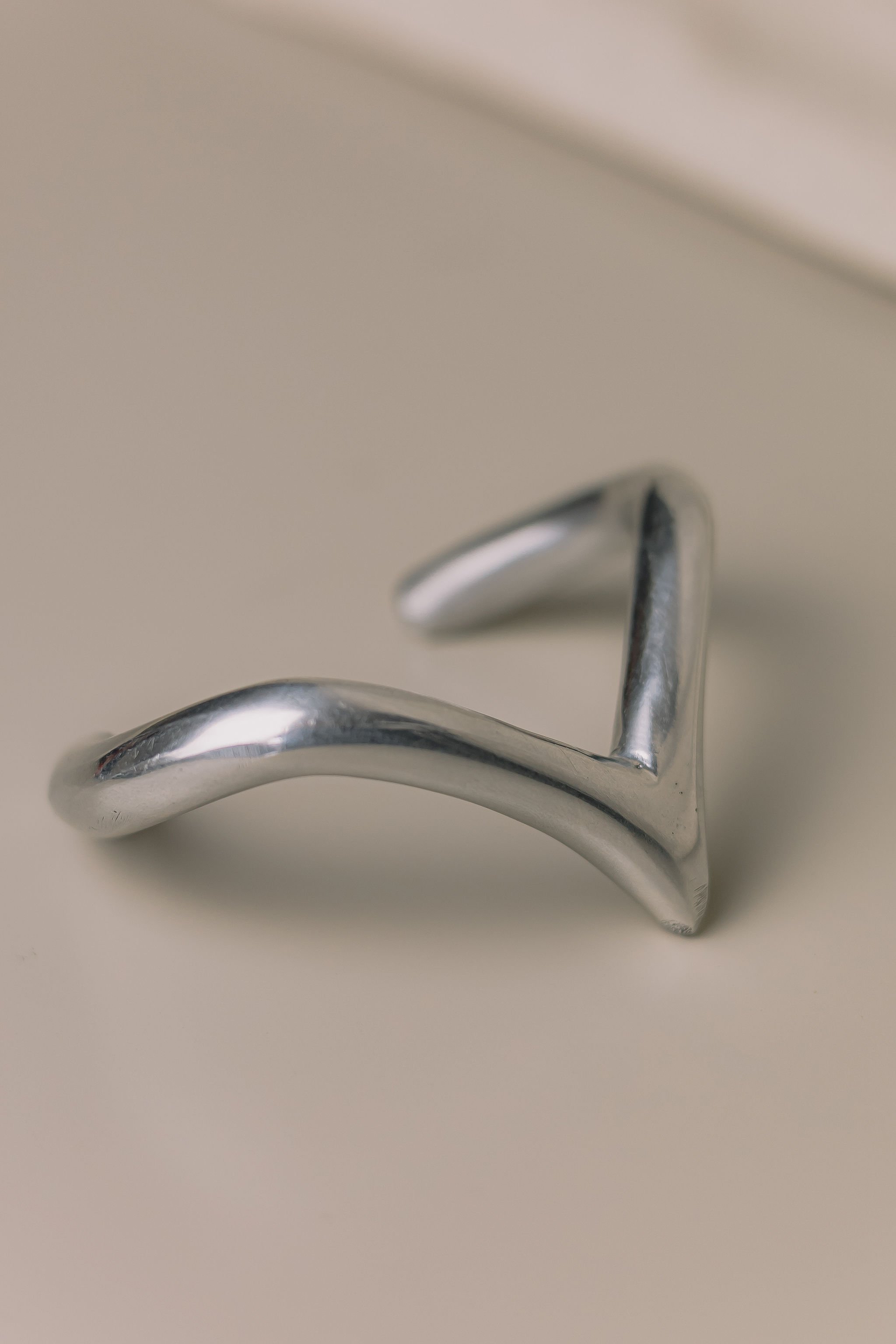 Close-up of a metallic hook resting on a light-colored surface.