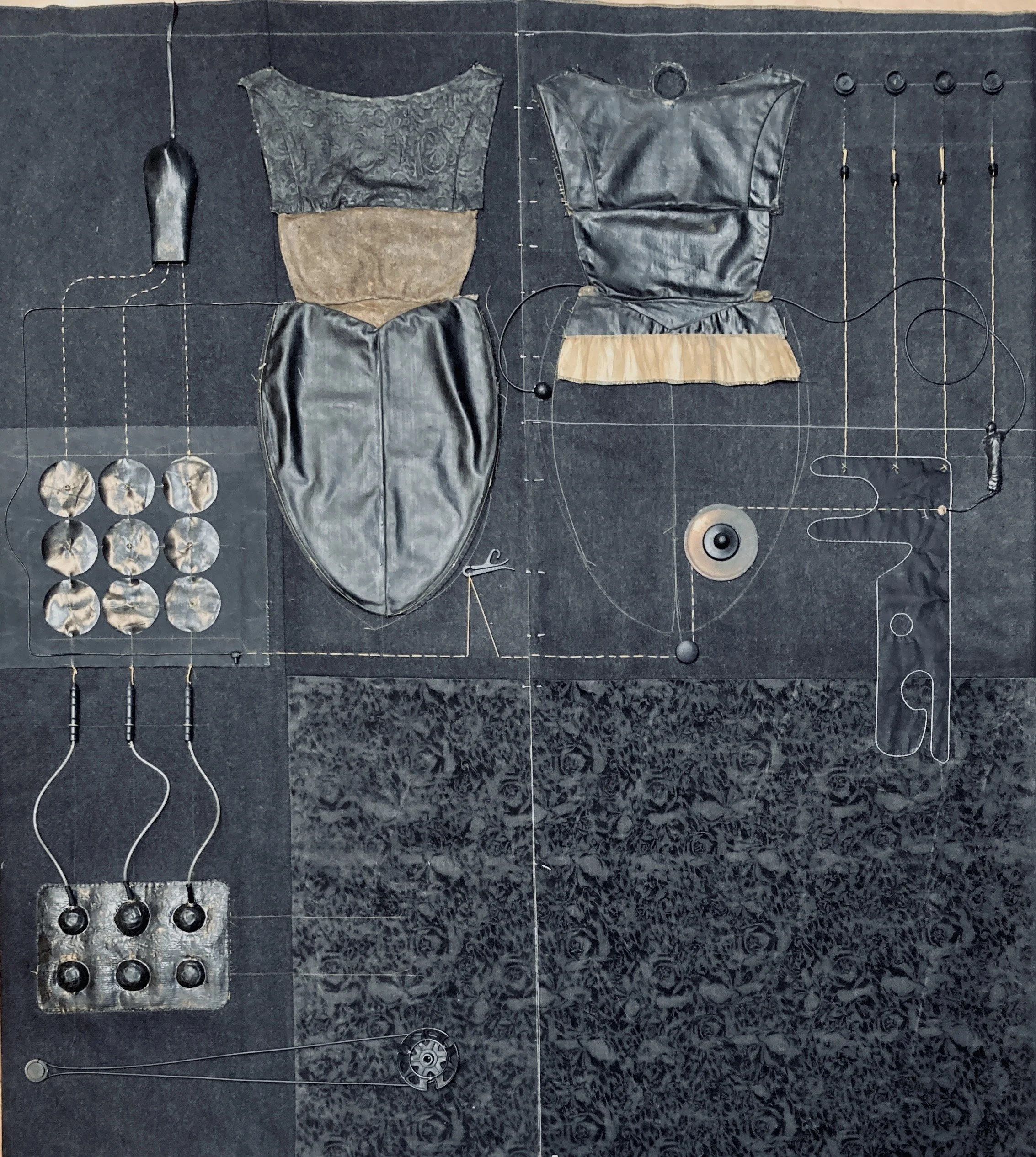 Künstlerisches Werk aus verschiedenen Materialien wie Leder, Stoff und Metall, angeordnet auf einer schwarzen Oberfläche, mit Zeichnungen und verbundenen Elementen, die an eine technische oder textile Komposition erinnern.