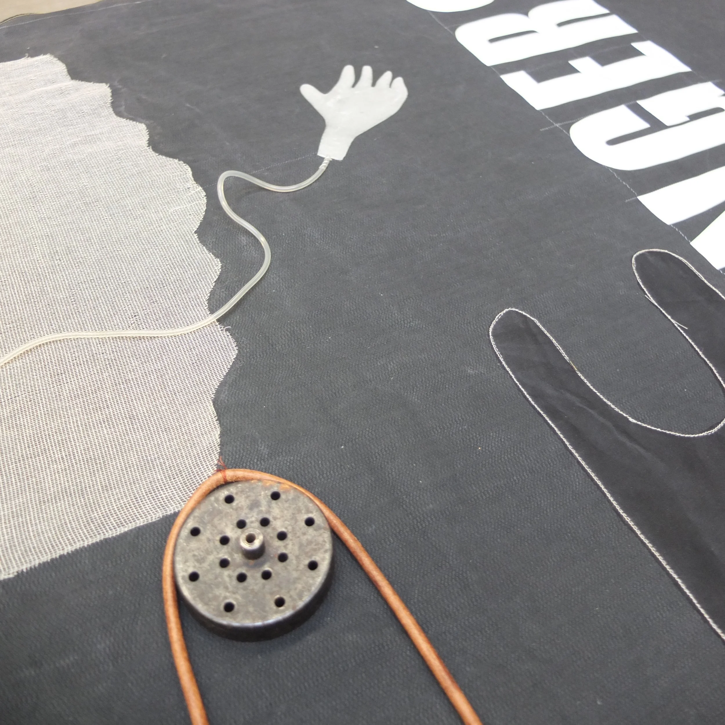 Kunstwerk mit einer weißen Handschuh-Silhouette, verbunden mit einem Kabel, auf schwarzem Hintergrund mit weißen Buchstaben.