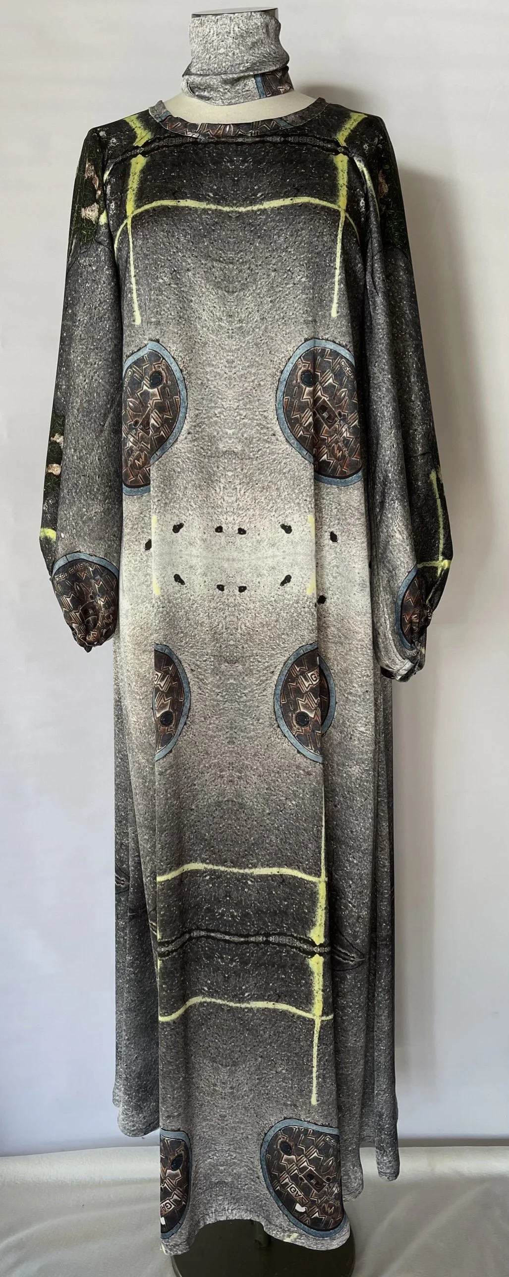 Full-length dress on mannequin featuring a print of a manhole cover design and a turtleneck.