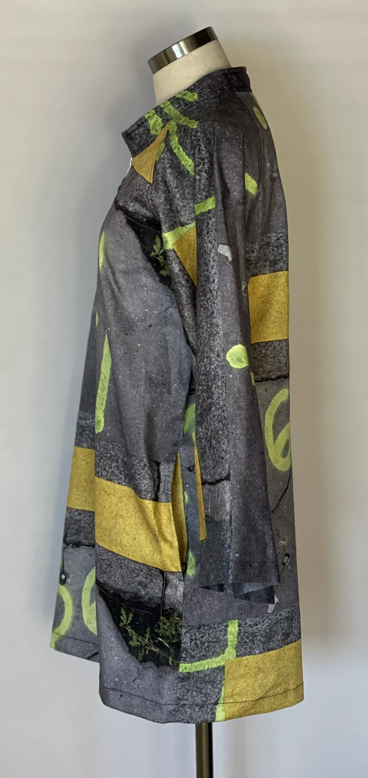 Long sleeve shirt with a graphic pattern of concrete and yellow caution tape with green foliage accents.