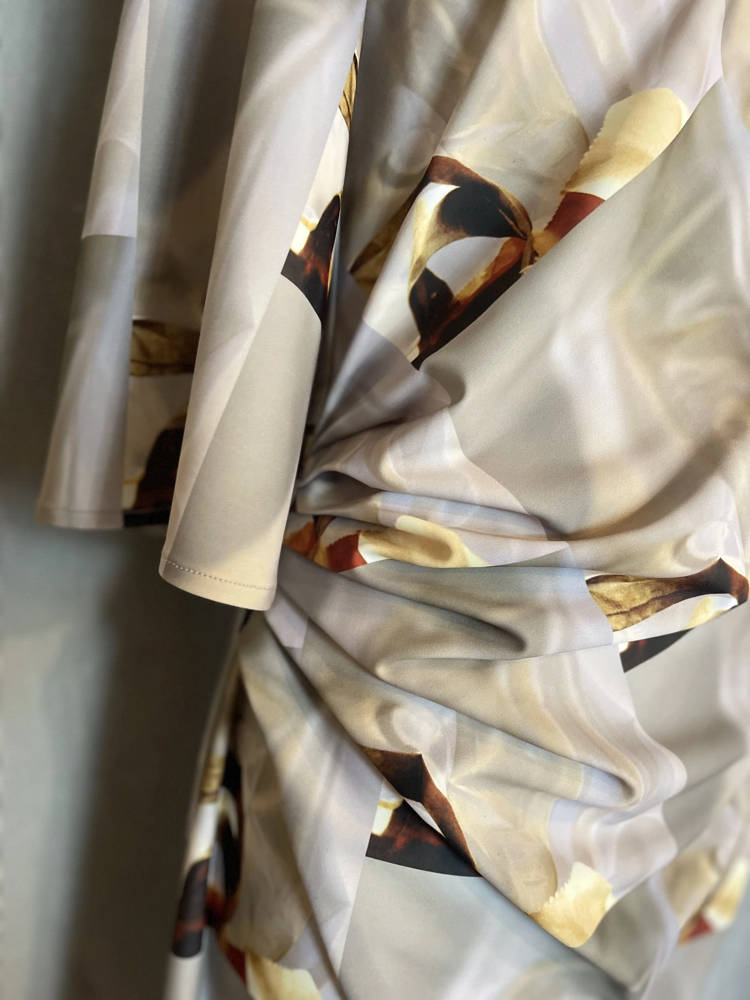 Close-up of crumpled fabric with a floral or abstract pattern in beige, brown, and cream colors.