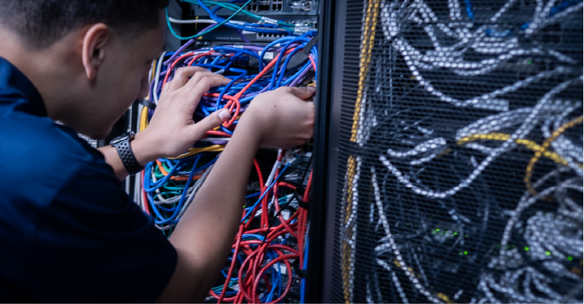 man in blue shirt touching wires in server room