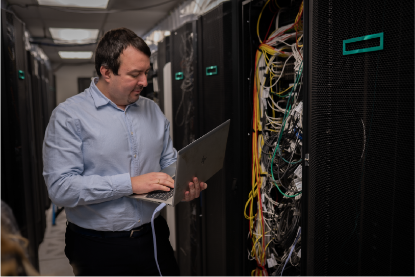 man holding laptop in server room
