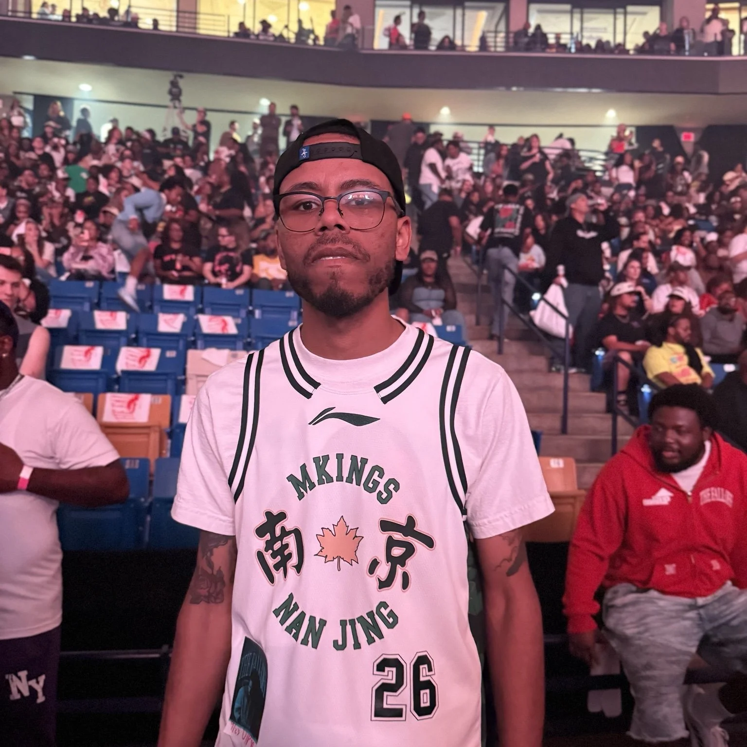 DaQuan at The Fall-Off concert in a white Man Jing jersey, with the arena crowd behind him.