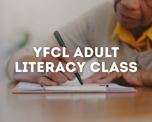 An elderly person writing in a notebook with a pen during an adult literacy class.