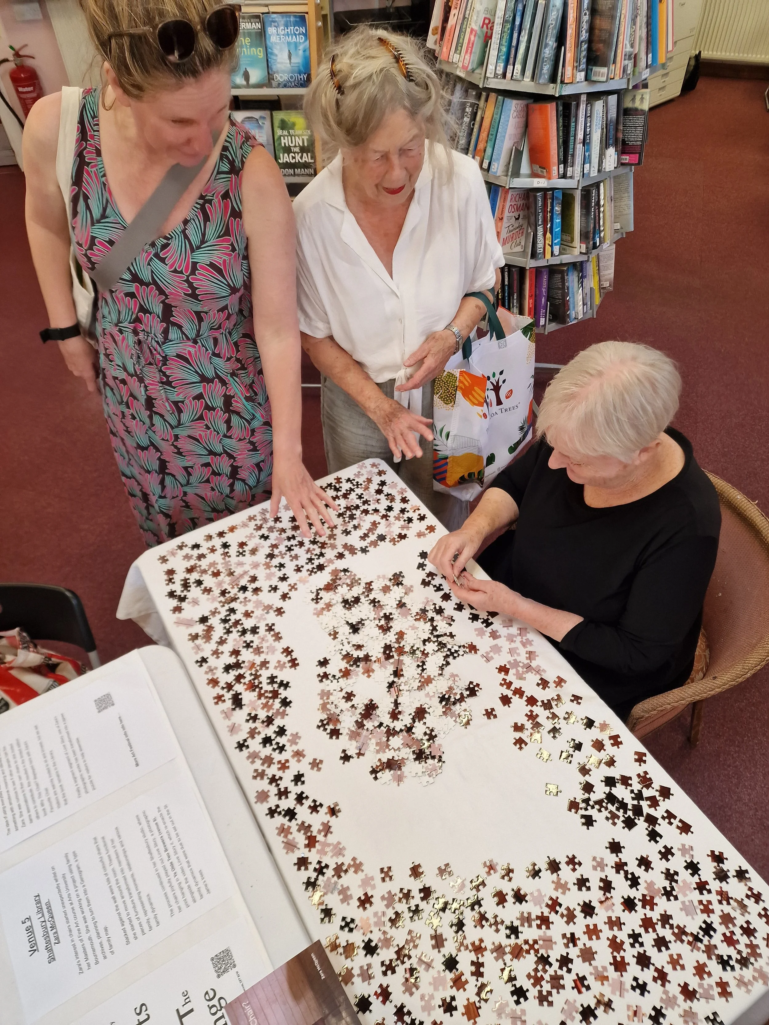 Zara McQueen's photographic print as a jigsaw puzzle alongside McQueen's Favourite Chair and her book Why This Chair? in the Library.
