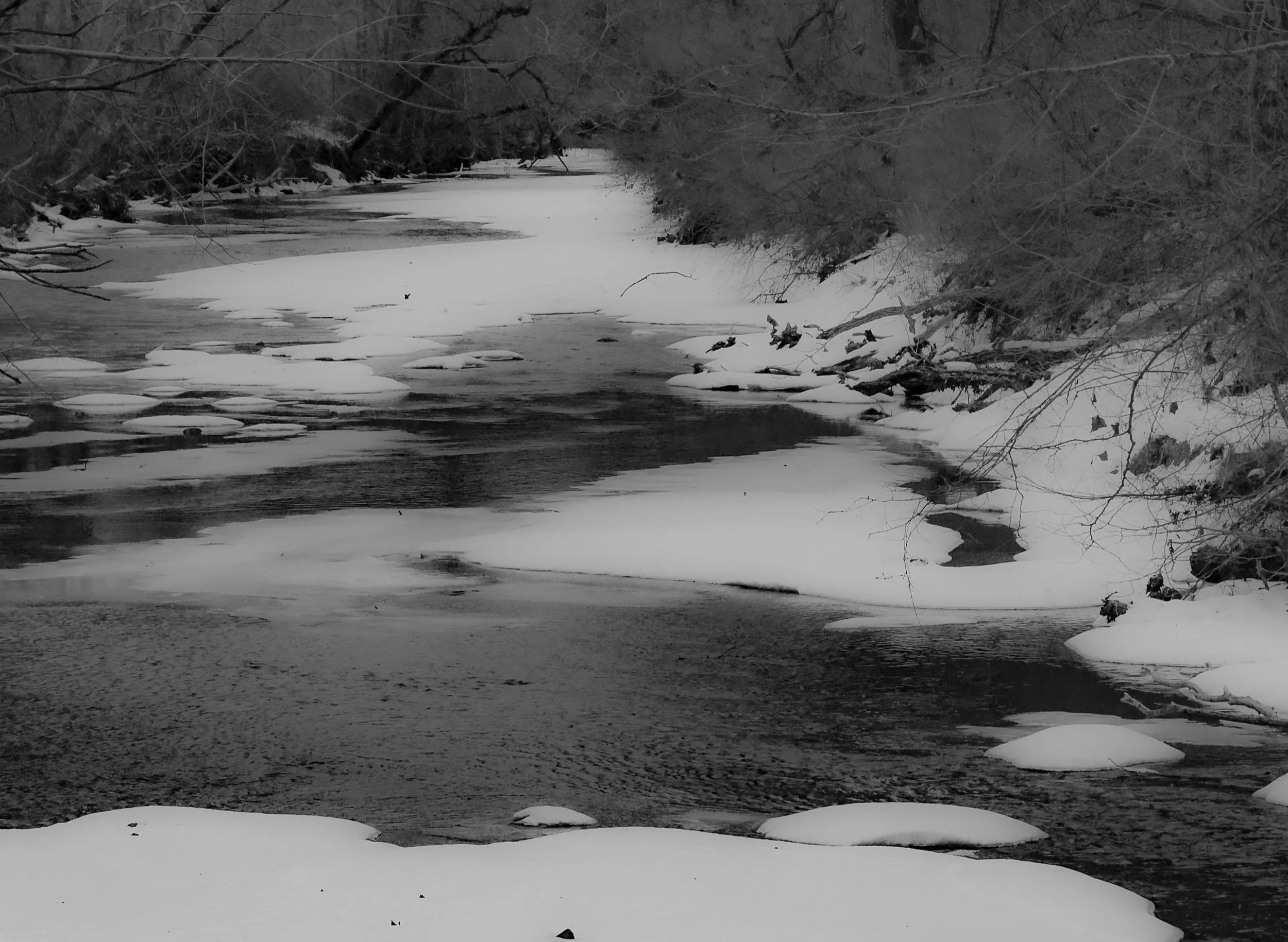 Gentle winter current moving through calm water and snow.