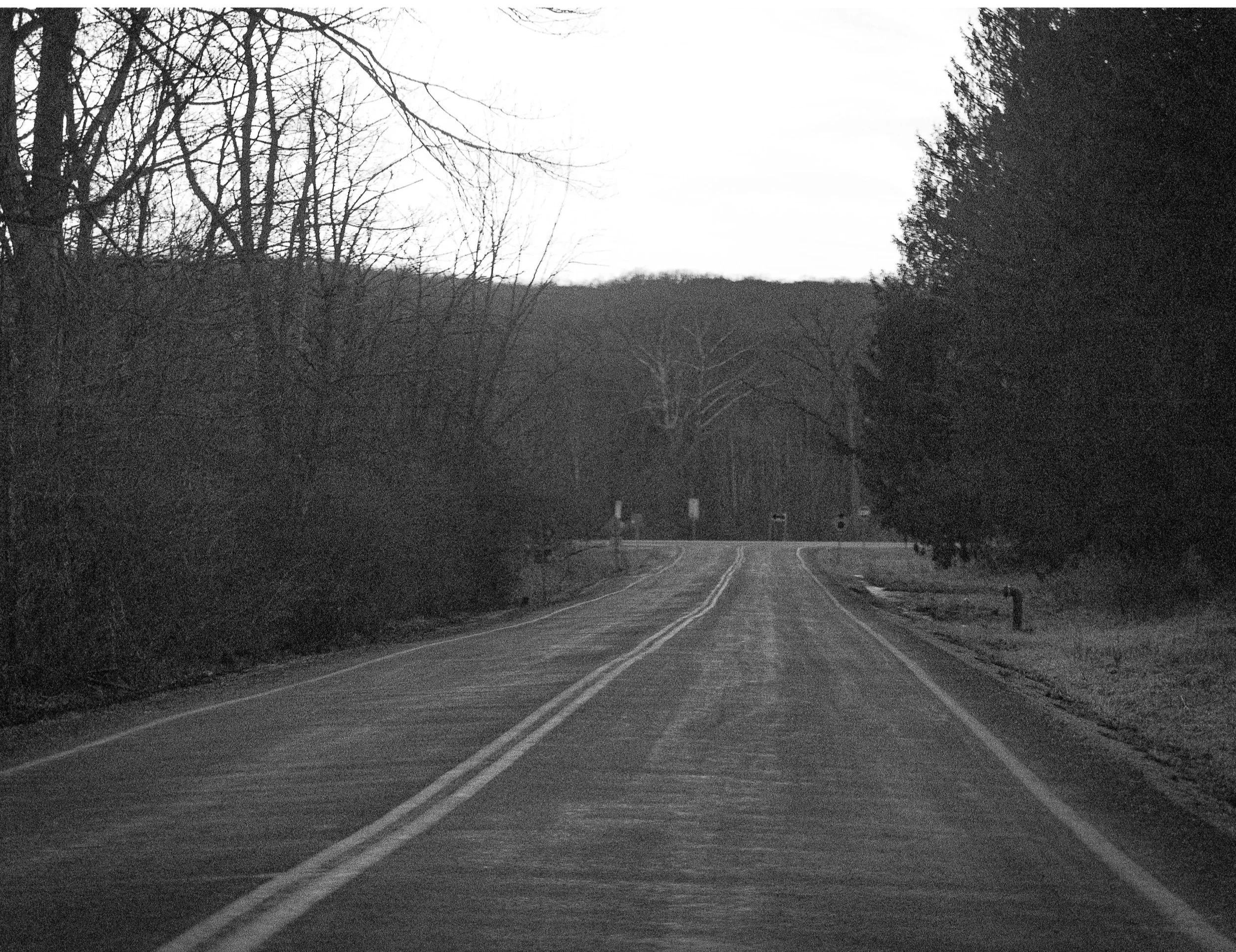 Quiet rural road leading into distant hills.