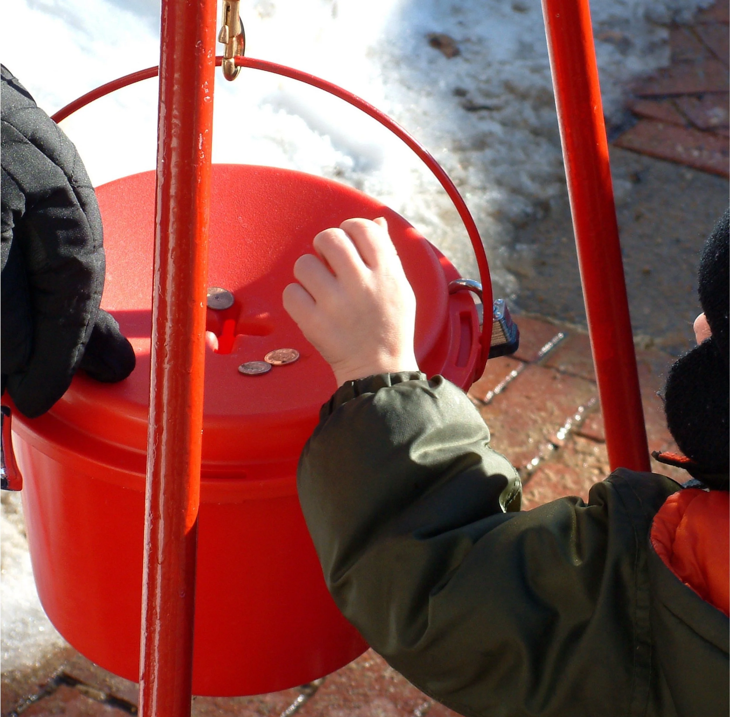 A child putting money into a Salvation Army Red Kettle