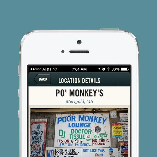 A smartphone screen displaying location details for PO' MONKEY'S in Merigold, Mississippi, with various signs and posters visible in the background of the location.