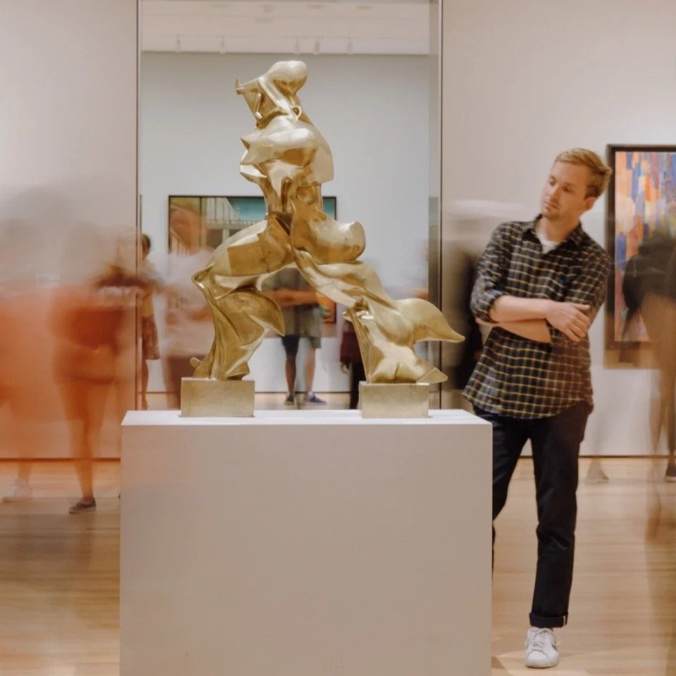 Man looking at a gold impresionistic sculpture in the museum gallery