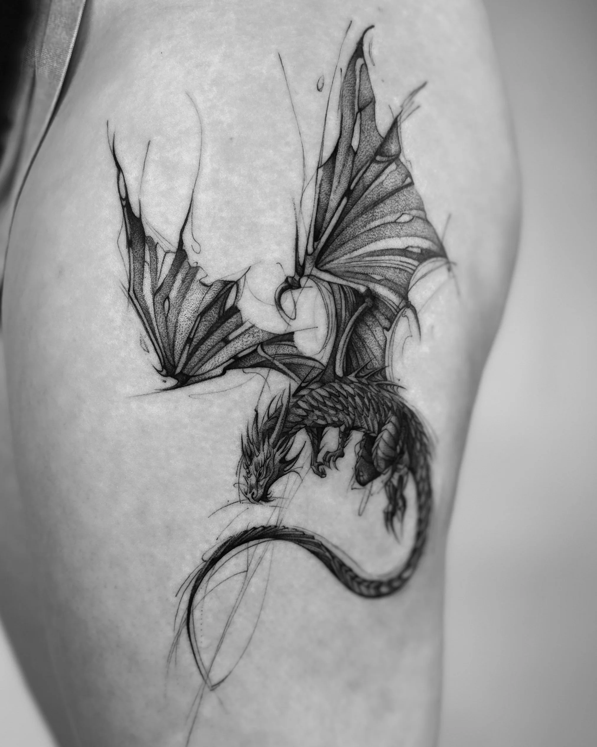 A detailed black and white tattoo of a dragon intertwined with a butterfly, showcasing intricate line work and shading.