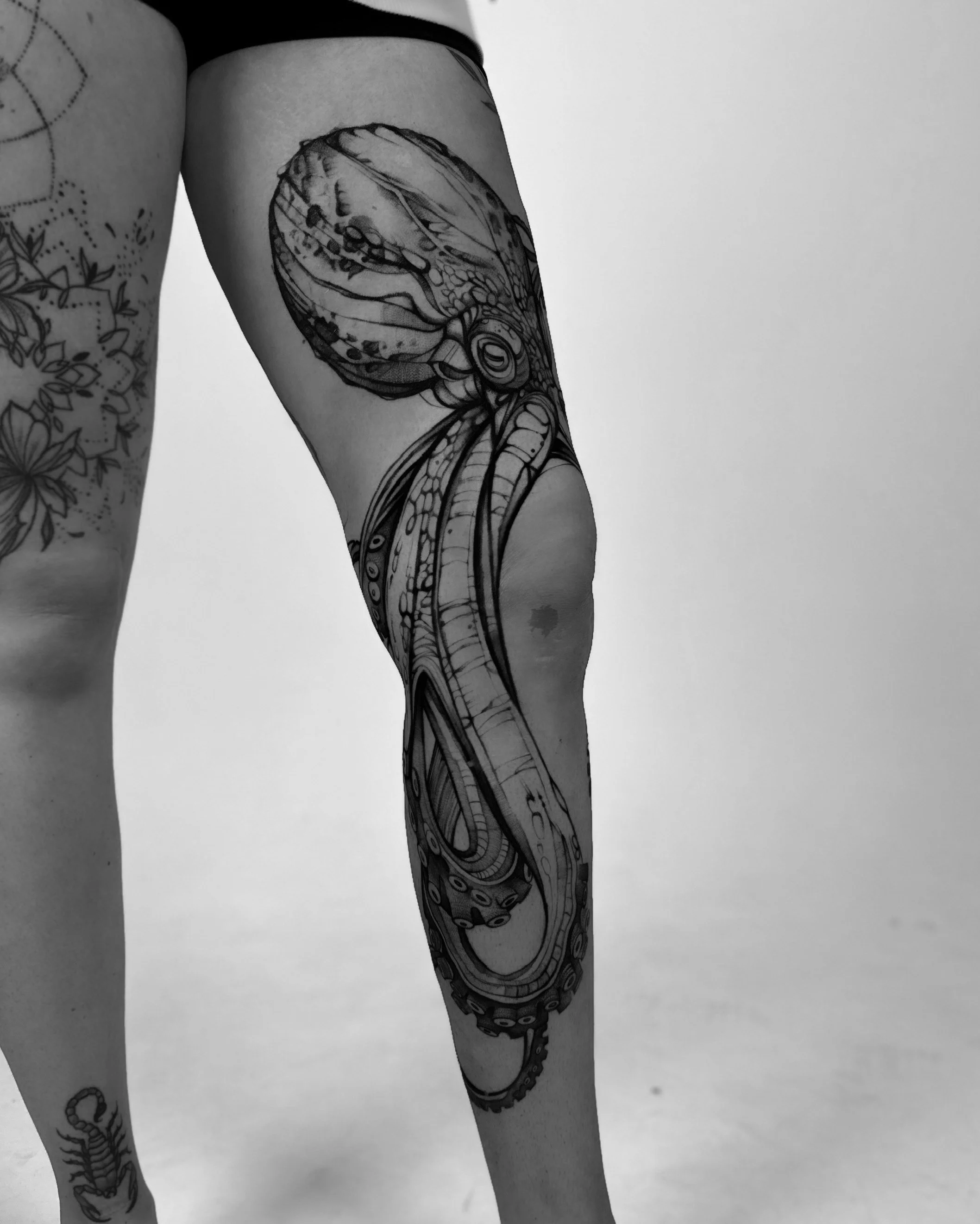 Black and white photograph of a person's arm with a detailed tattoo of an octopus.
