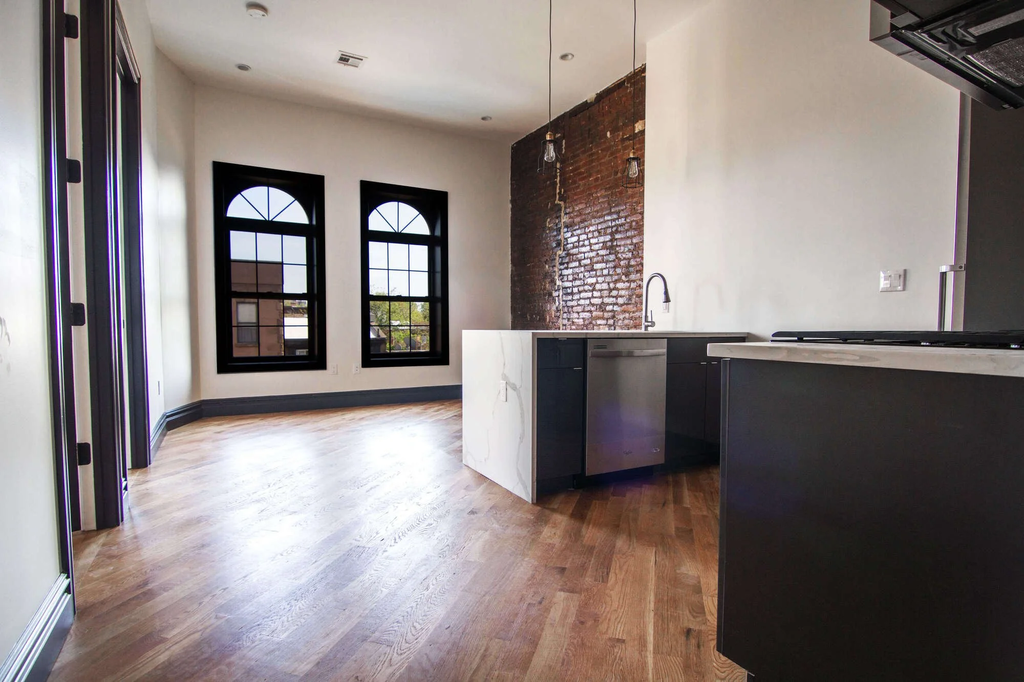 interior remodel of kitche, brock wall, 2 windows aith black window panes, and kitchen island