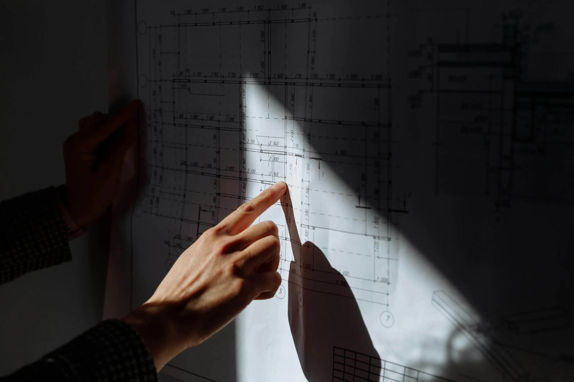 man's hand pointing at project plans with sahdaws