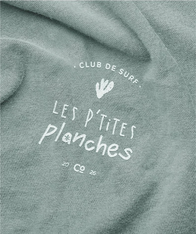 Vêtements en tissu vert avec un logo blanc de club de surf 'Les P'tites Planches'.