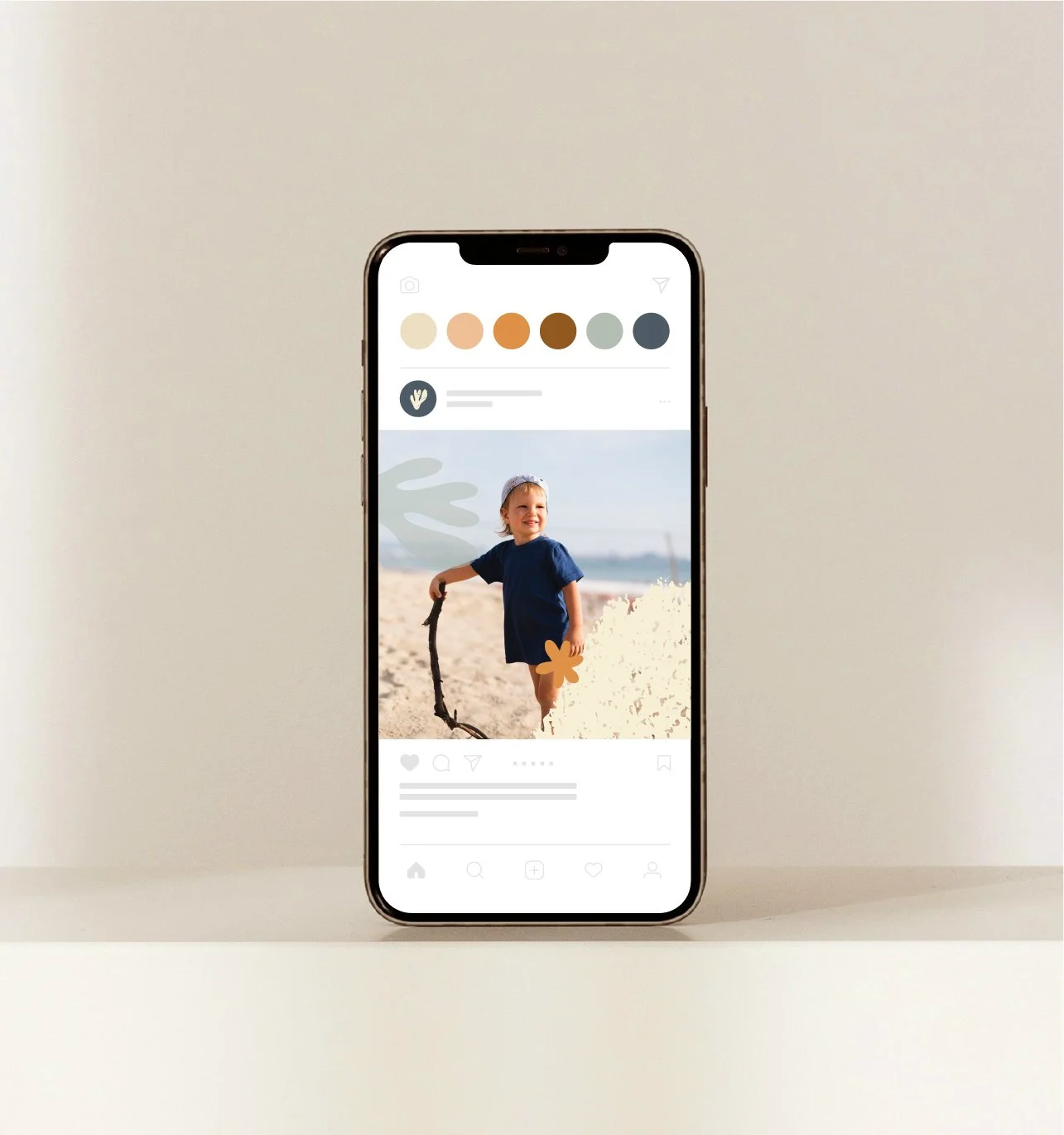 Un téléphone affichant une photo d'un enfant jouant à la plage, avec une branche dans la main, sous un ciel clair, réalisation du studio Hello Jane