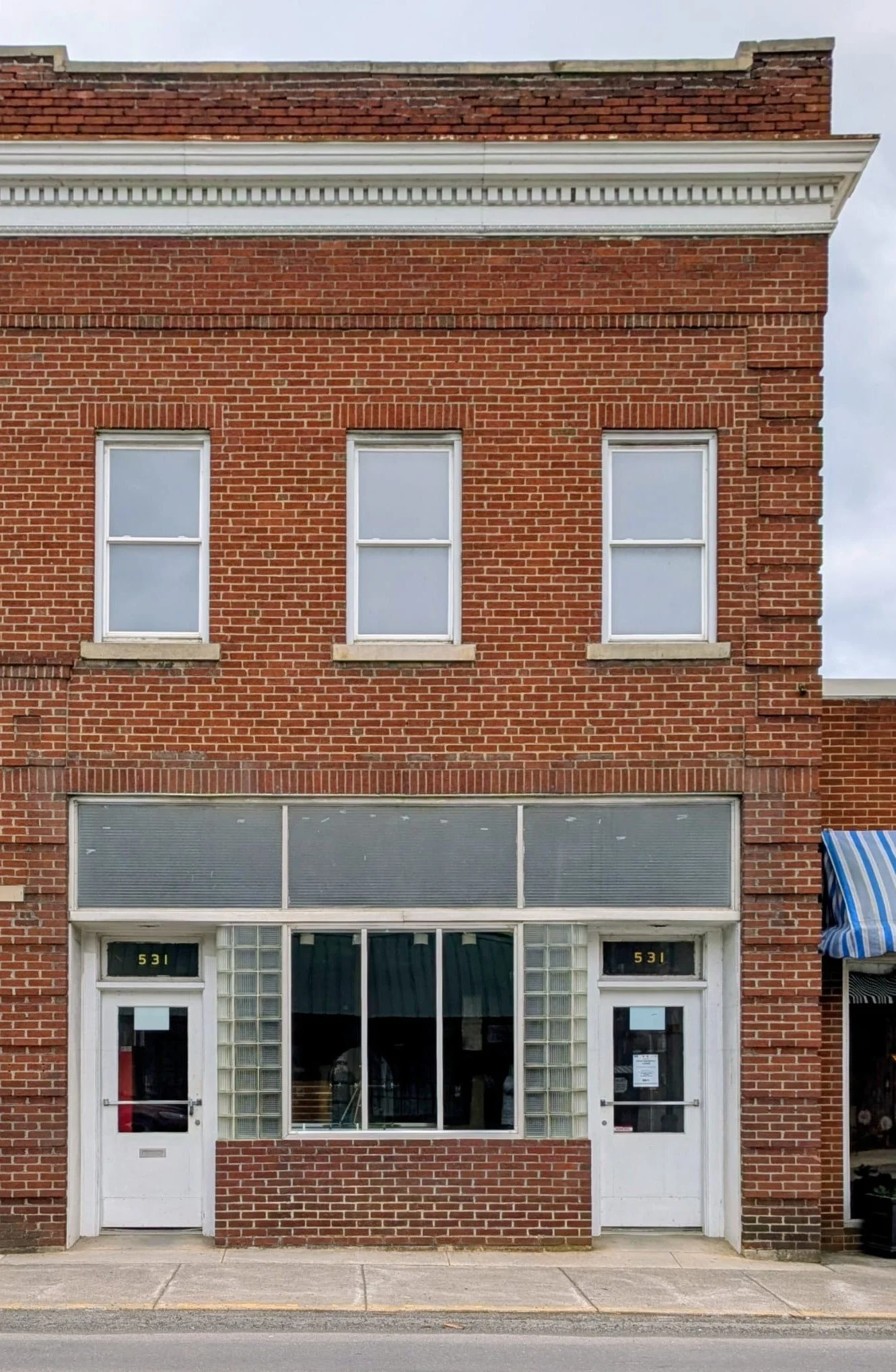 Brick building with two upper windows, a large lower window, and two doors labeled 531.