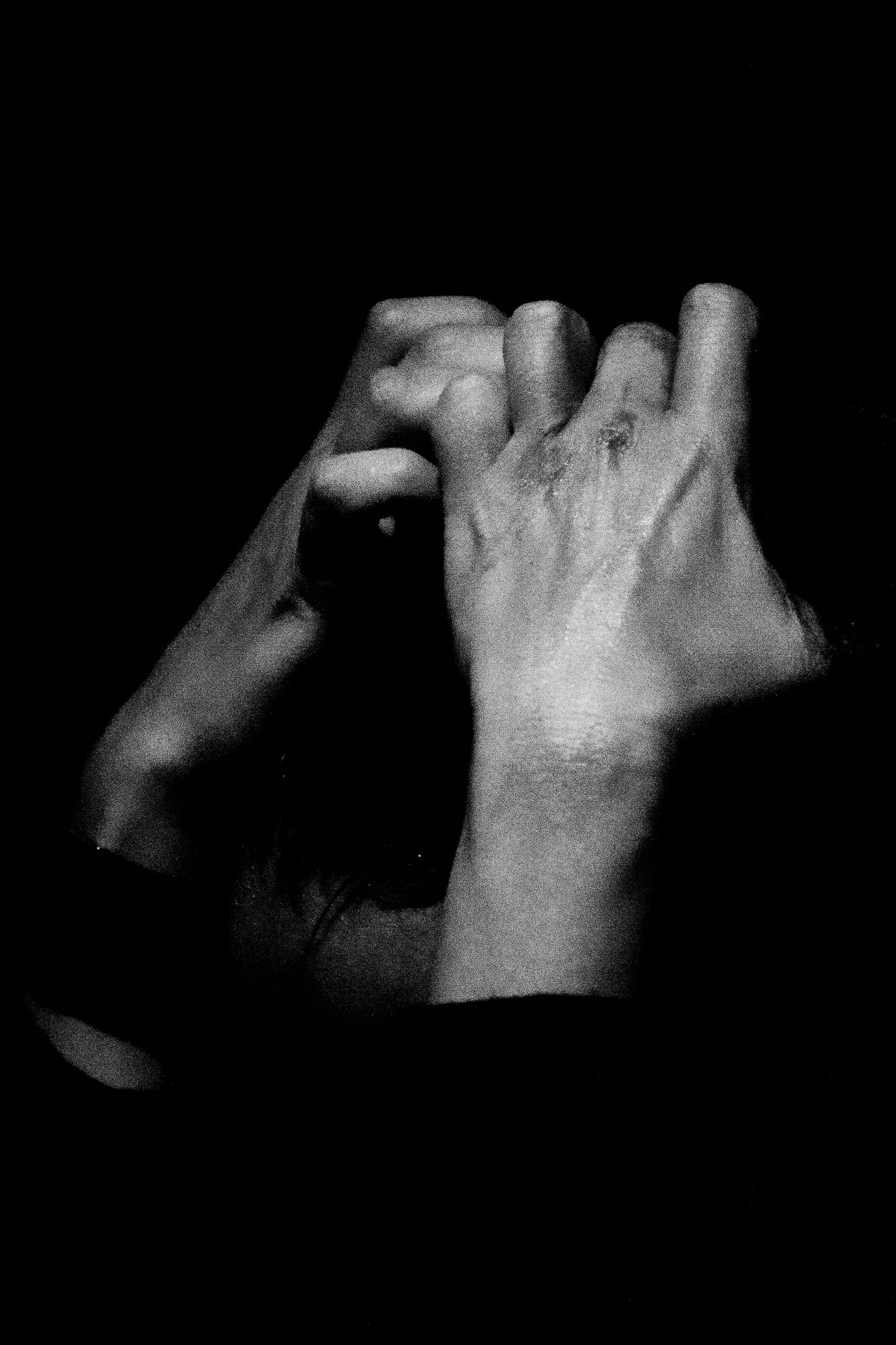 Deux mains entrelacées dans une posture de soutien ou de connexion, en noir et blanc.