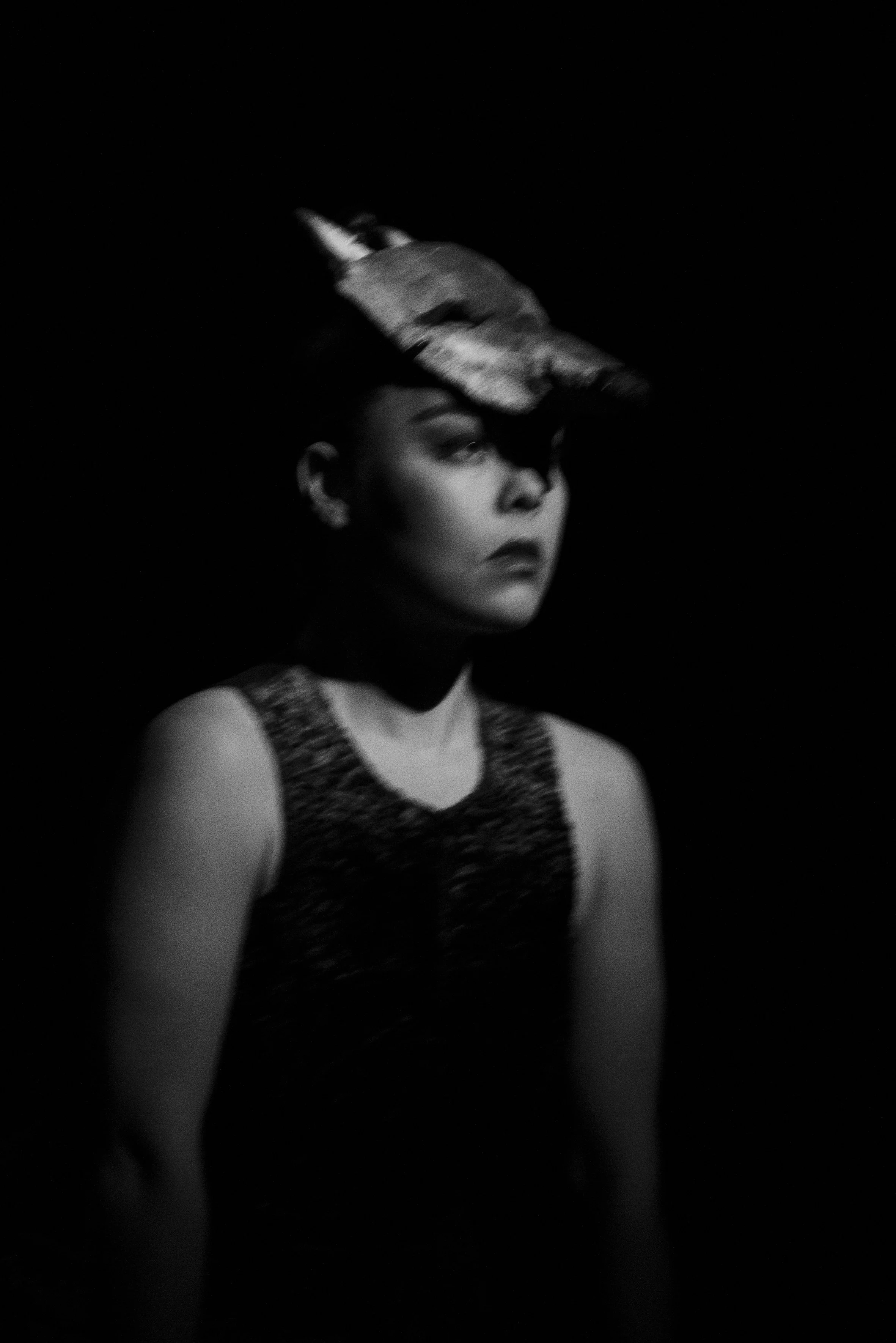 Une femme en noir et blanc portant un masque de licorne sur la tête, debout dans l'obscurité.