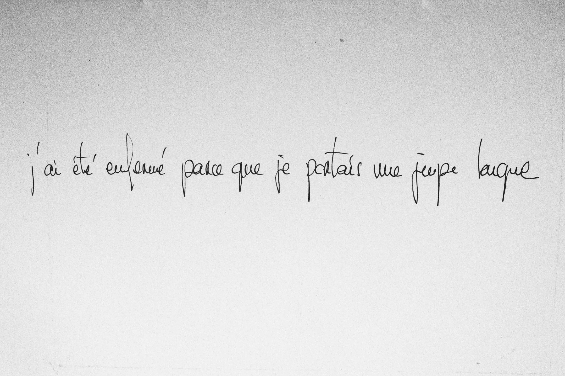 Une photo d'une note manuscrite en français qui dit: 'j'ai été embrassé parce que je portais une jupe longue'.