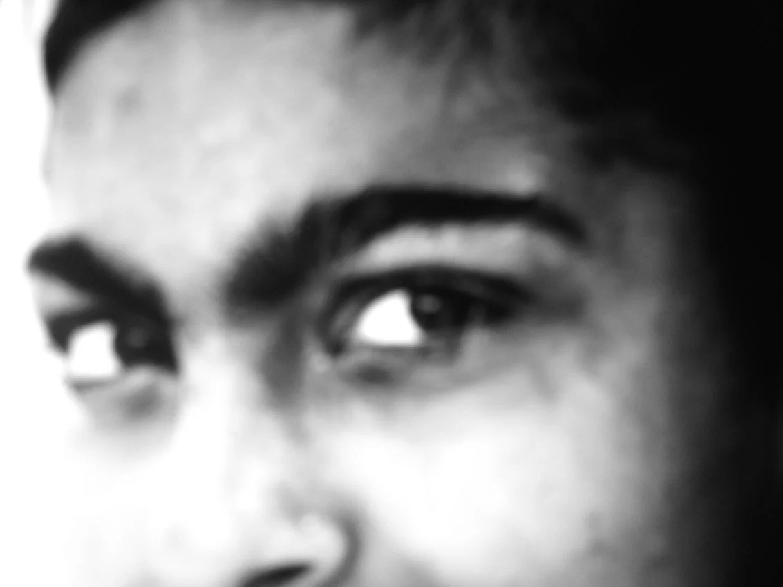 Un gros plan d'une personne dont l'œil et le sourcil sont visibles, en noir et blanc.