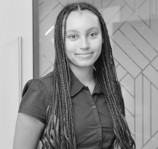 Close-up of a woman with dark hair and glasses inside a building with stained glass windows