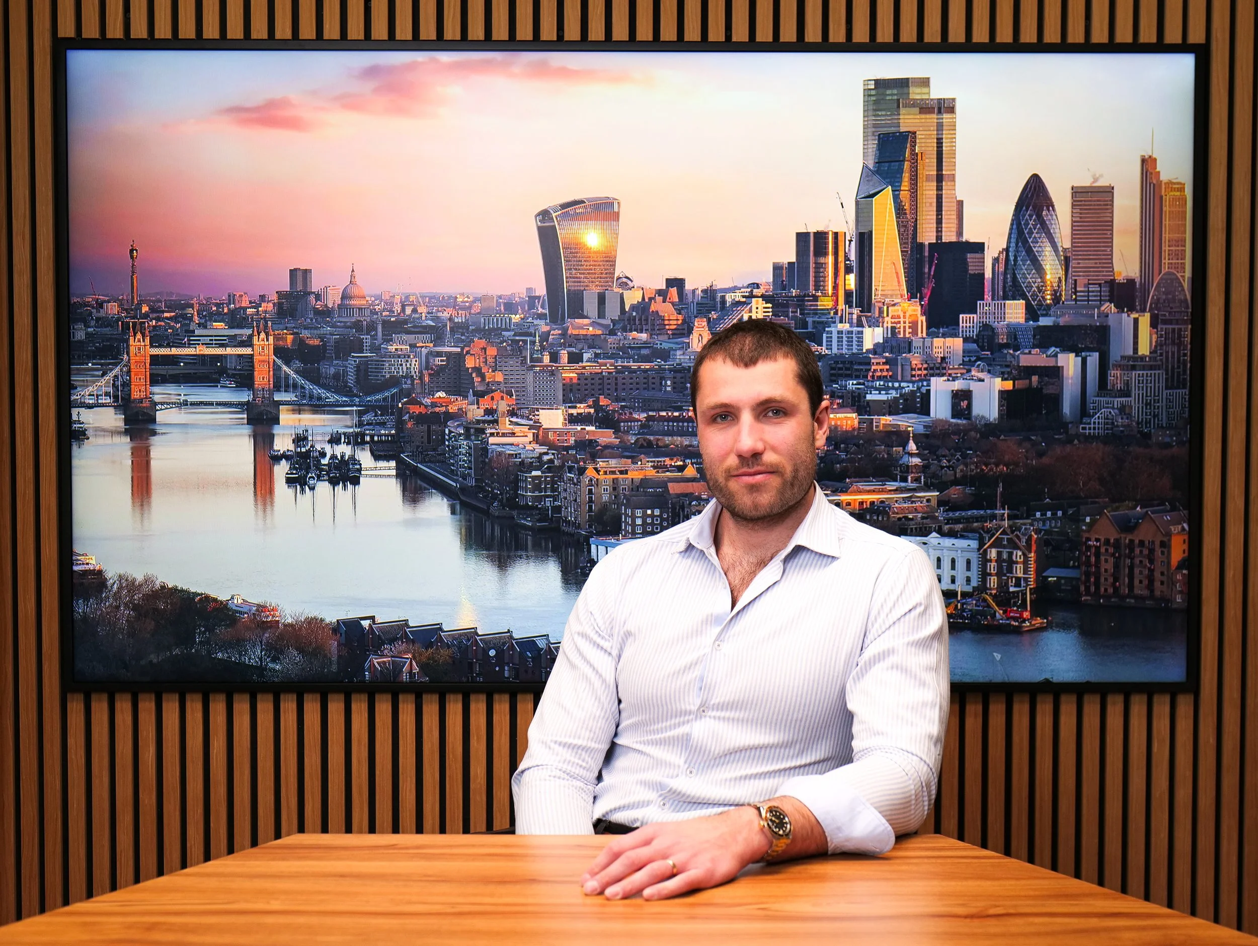 A man with a beard and short dark hair, wearing a CITY AM jacket, hands out a magazine on a city sidewalk with Us and St. Paul's Cathedral in the background.