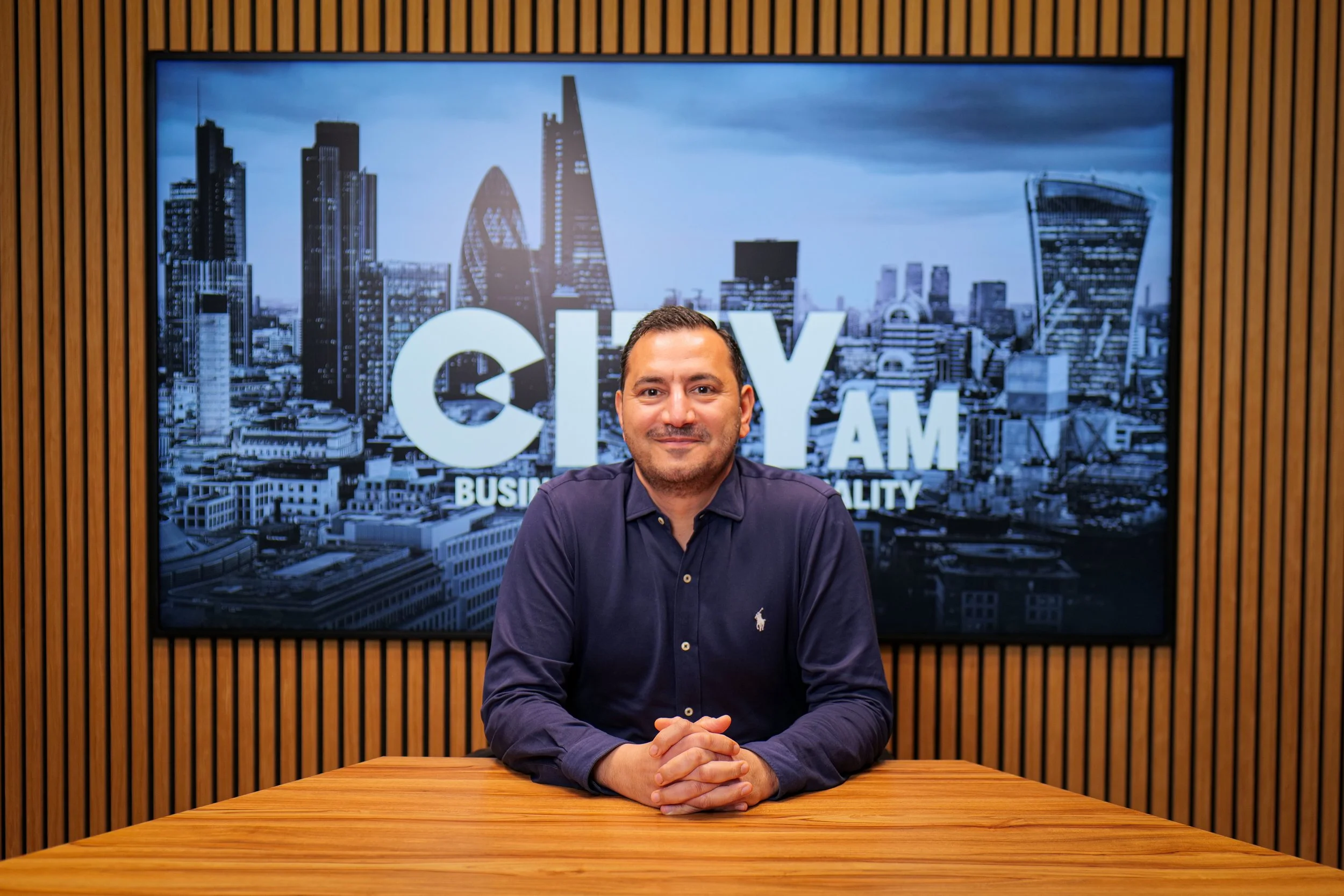 Black and white portrait of a man with slicked-back hair, wearing a patterned button-up shirt, smiling slightly, against a plain background.