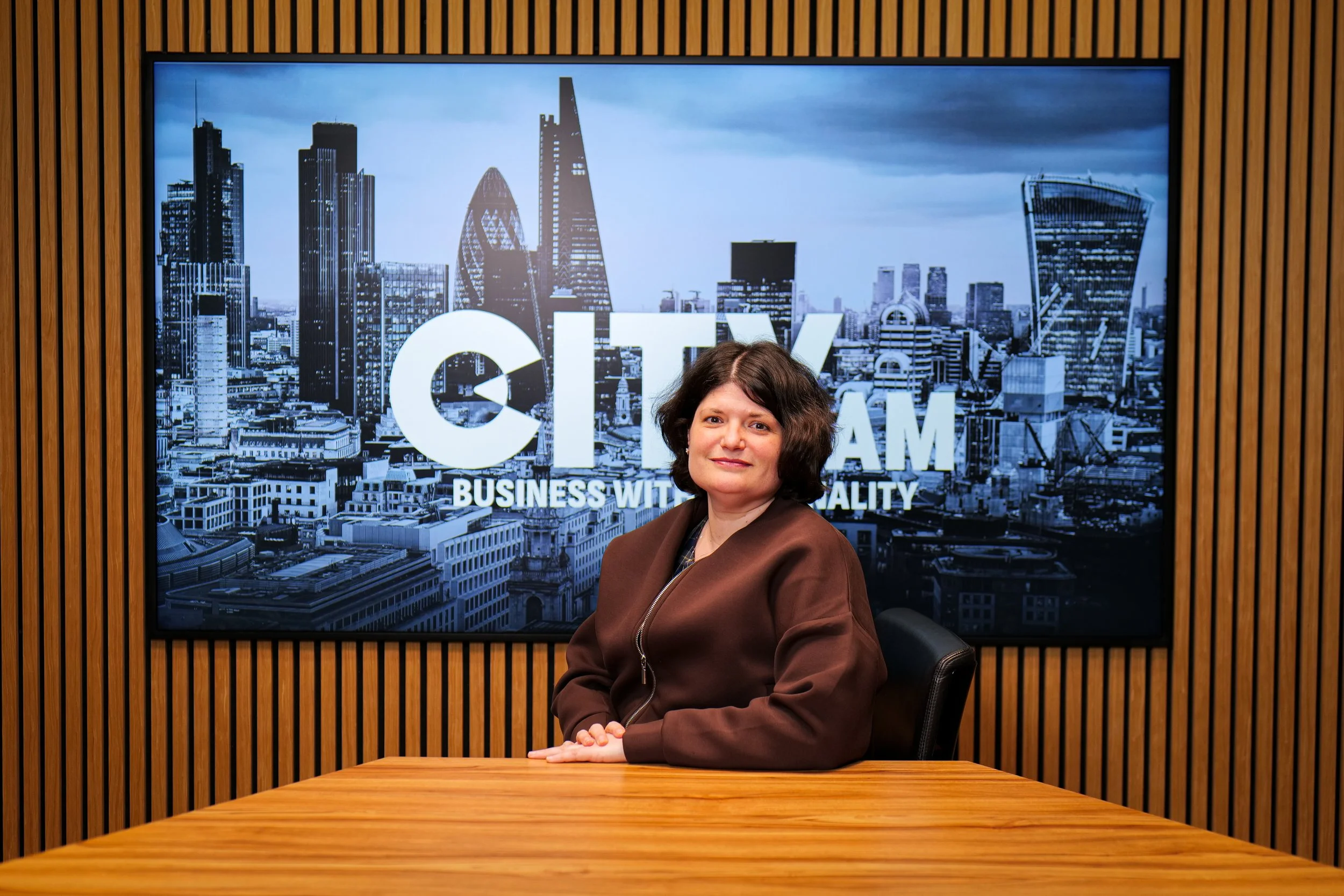 Close-up of a woman with dark hair and glasses inside a building with stained glass windows