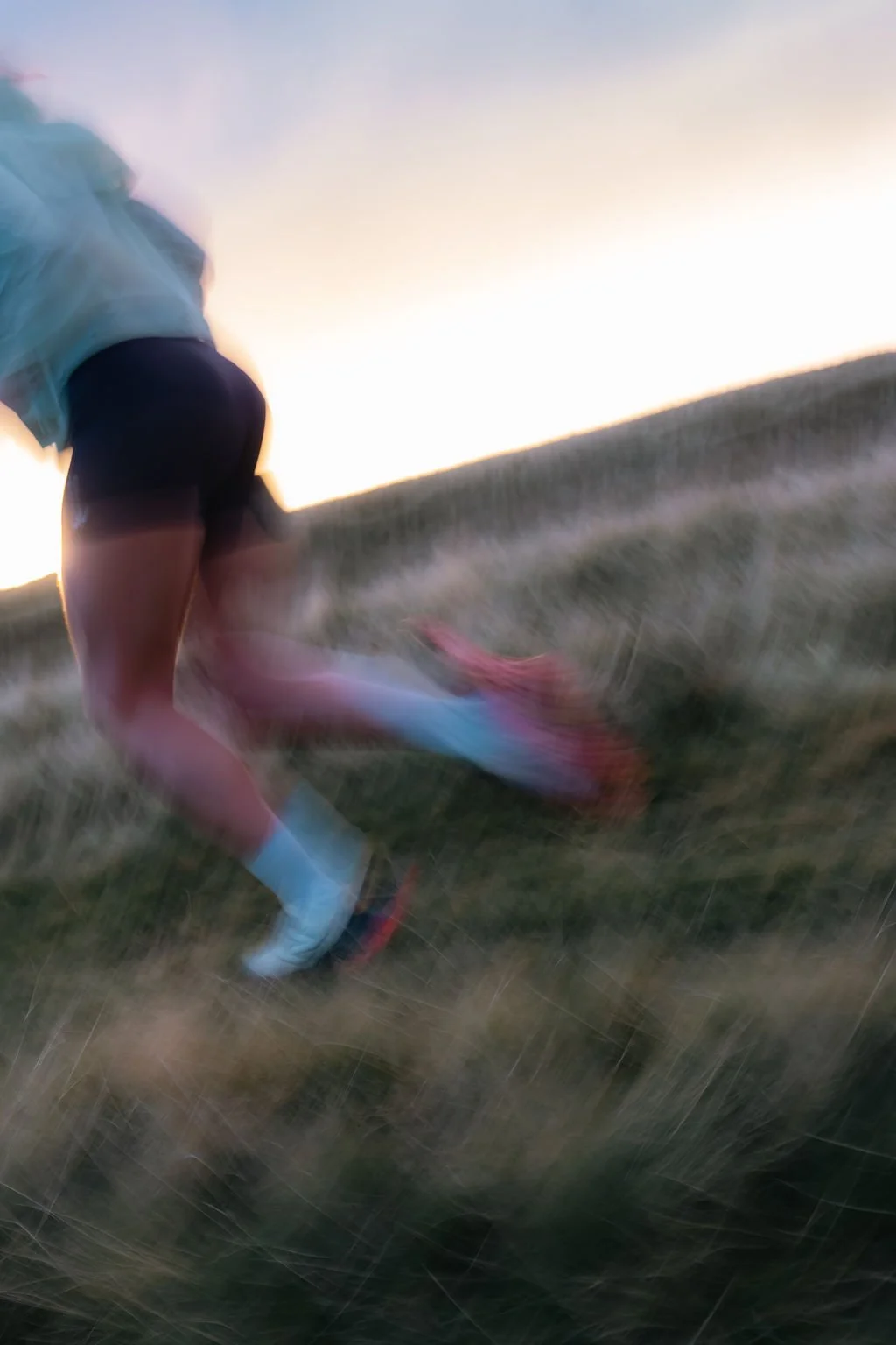 Person running outdoors in a grassy field during sunset.