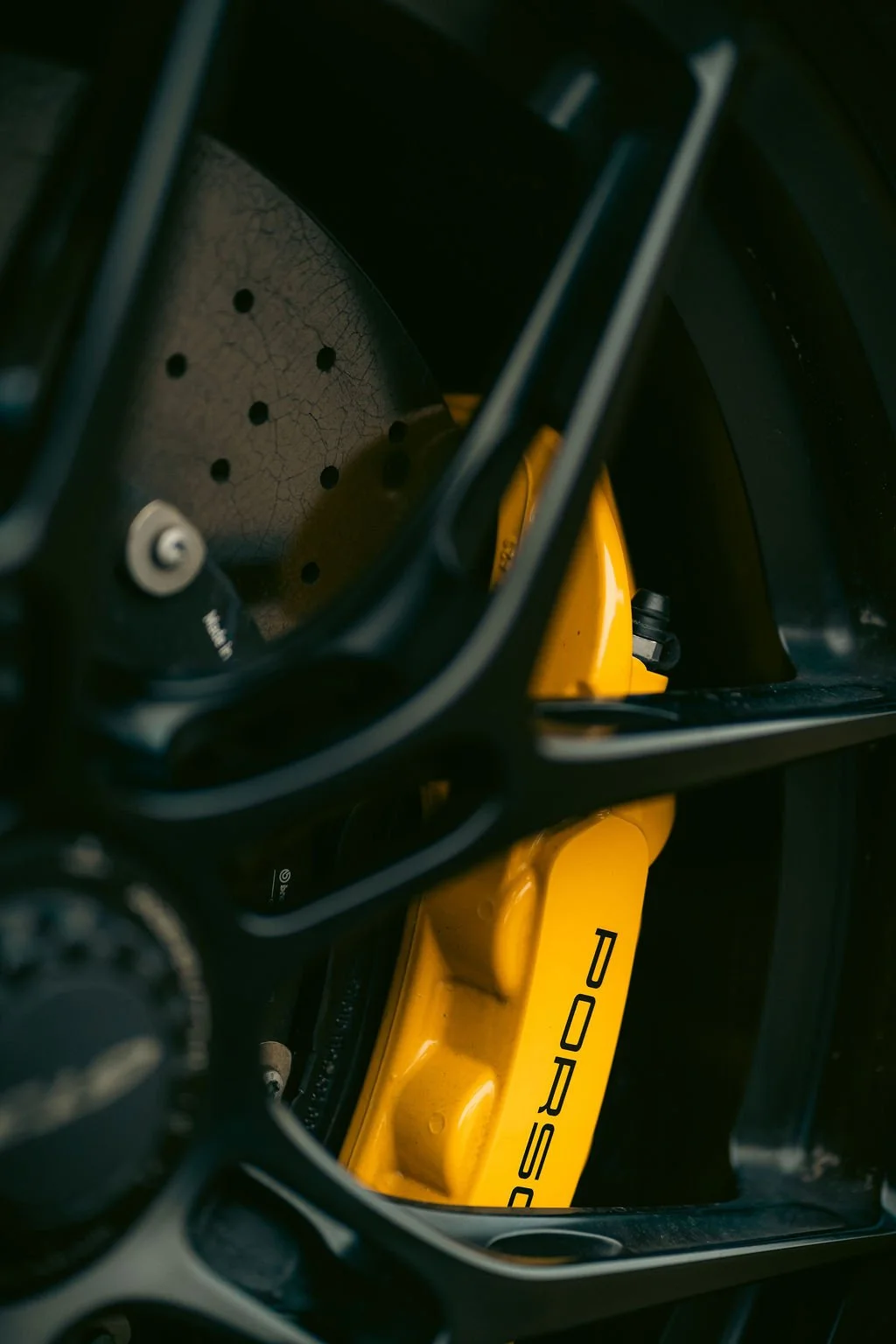 Close-up of a yellow Porsche brake caliper through a race helmet's visor.