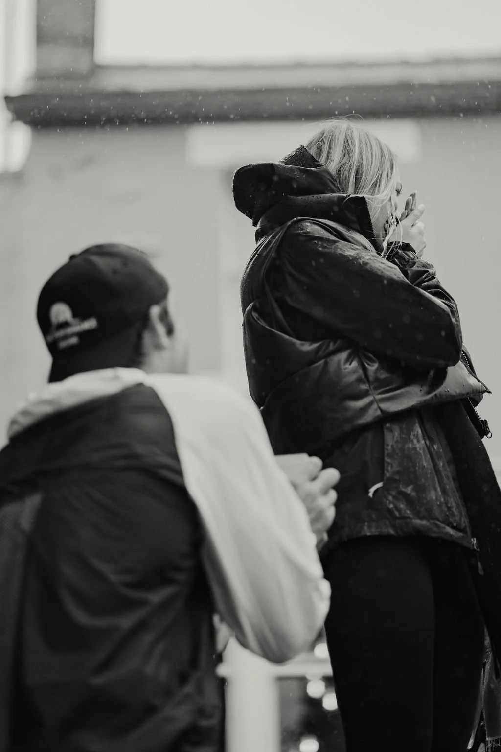 A woman standing, being proposed to by a man who is down on one knee.