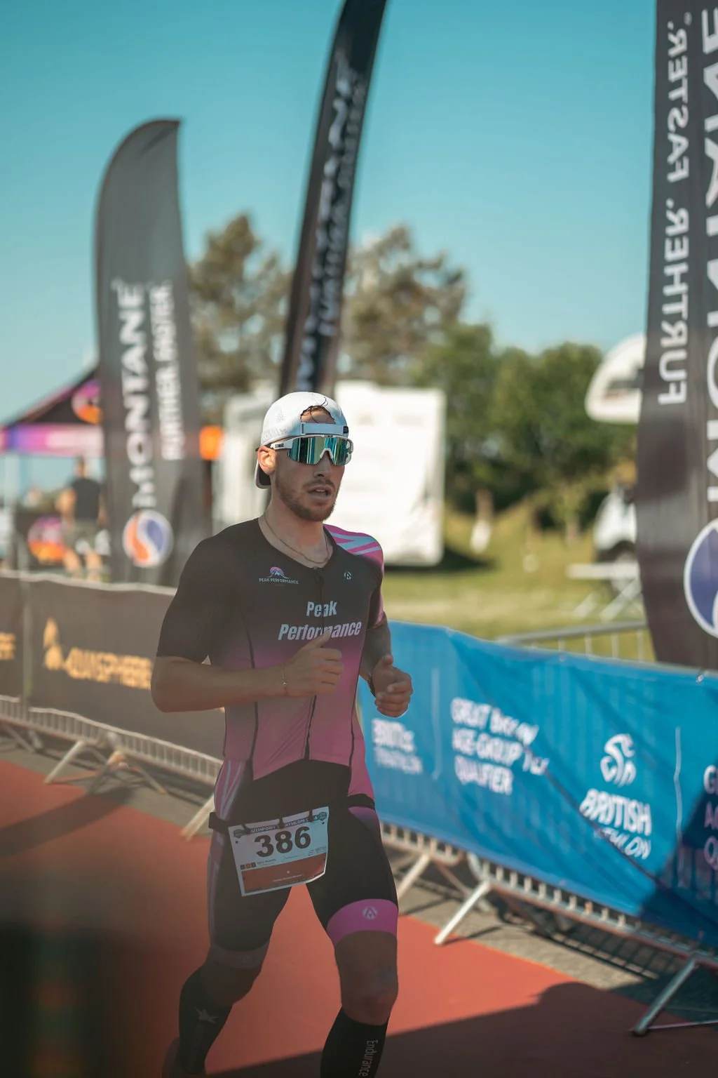 Male runner wearing sunglasses, a cap, and a black and pink athletic suit with a race number 386, participating in a marathon or race event.