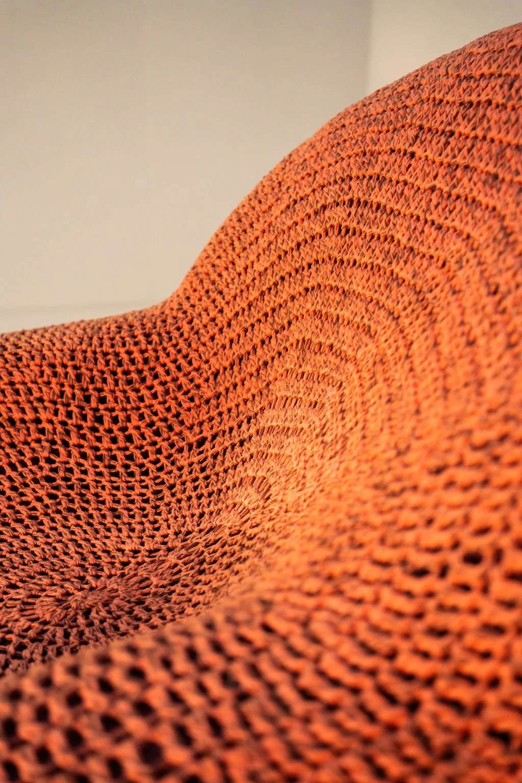 Close-up of an orange knitted fabric with a textured pattern.
