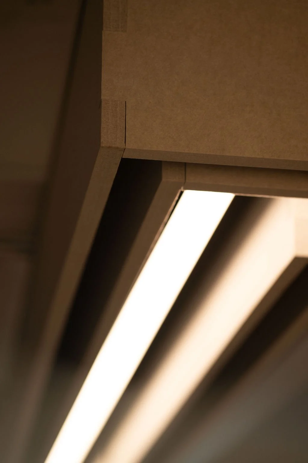Close-up of wooden architectural beams with integrated lighting in a modern ceiling design.