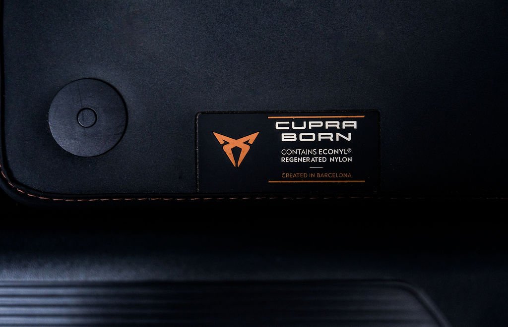 Close-up of a black object with a circular attachment and a label that reads 'CUPRA BORN' with the logo, indicating it contains Econyl regenerated nylon, created in Barcelona.