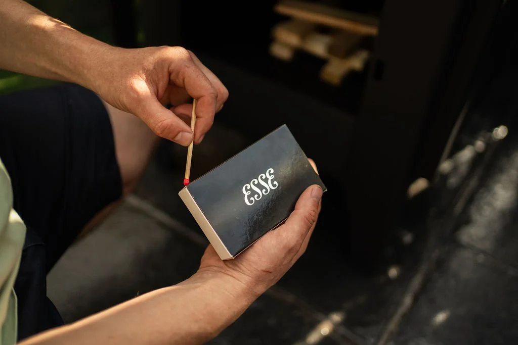 A person lighting a match next to a pack of Essee matches.